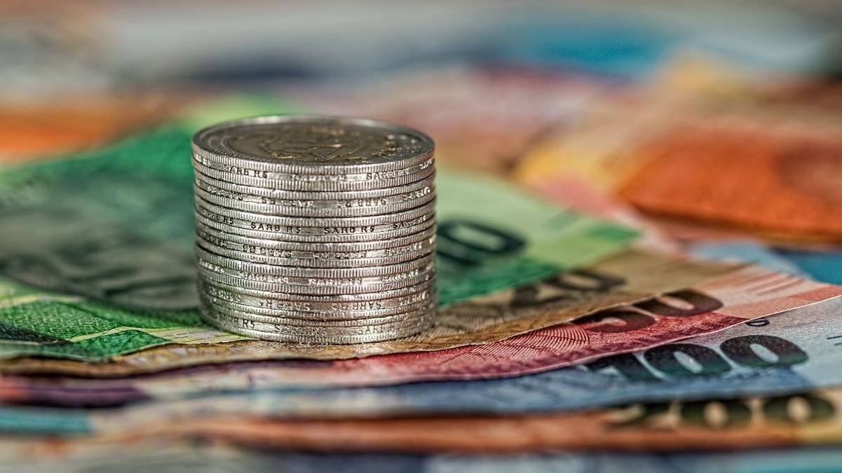 Стос срібних монет на розкладених різнокольорових банкнотах
